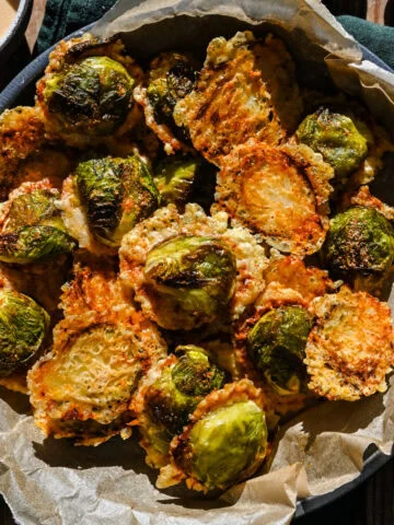Krispiga rostade brysselkål med parmesanost i en svart skål.