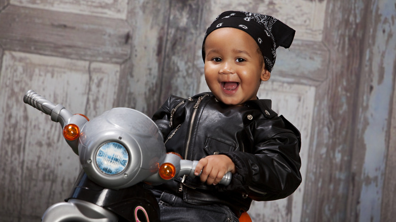 Baby i en skinnjacka på en leksaksmotorcykel
