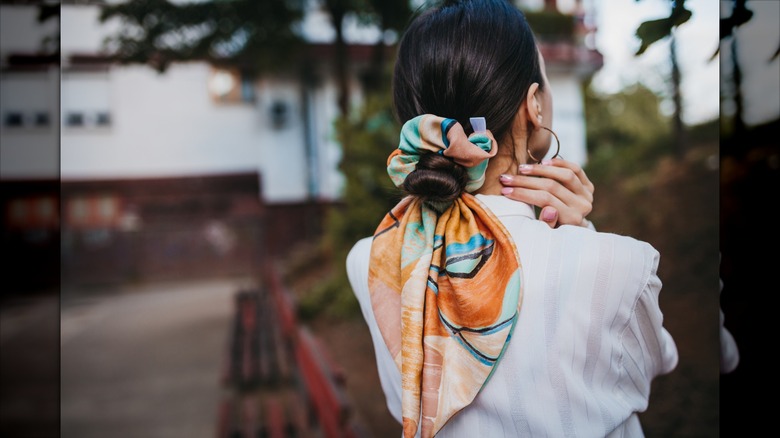 En brunett kvinna som bär håret i en bulle med en scrunchie i bandana-stil