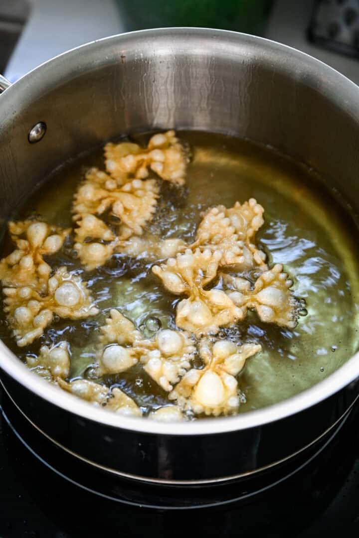 Närbild av fluga pasta som puffar i varm olja i en kastrull.