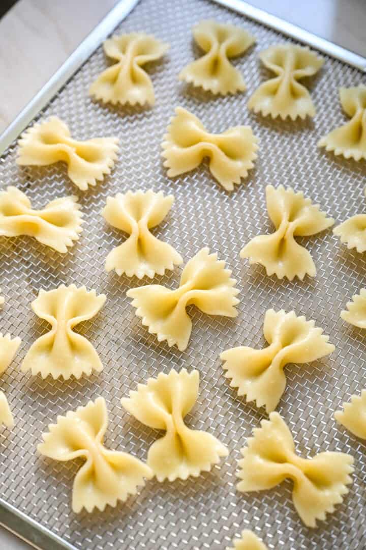 45 graders vy av kokt fluga pasta utspridda på en mesh dehydrator bricka.