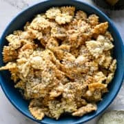 Ovanifrån av en blå skål med puffad pasta pudrad med parmesan och sprucken peppar.