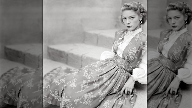 Lauren Bacall slappar på trappan i en vit blus och blommig pinaforklänning för tidningen Glamour i augusti 1949