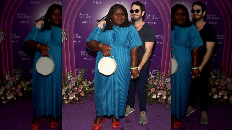 Gabourey Sidibe i blå klänning och röda skor poserar tillsammans med sin man Brandon Frankel