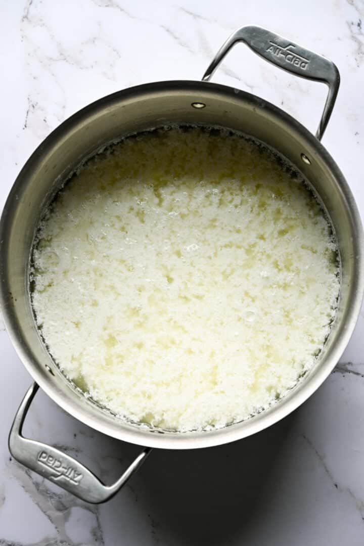 Vy ovanifrån av kesomassa separerad från vassle i en helt klädd kruka på marmor