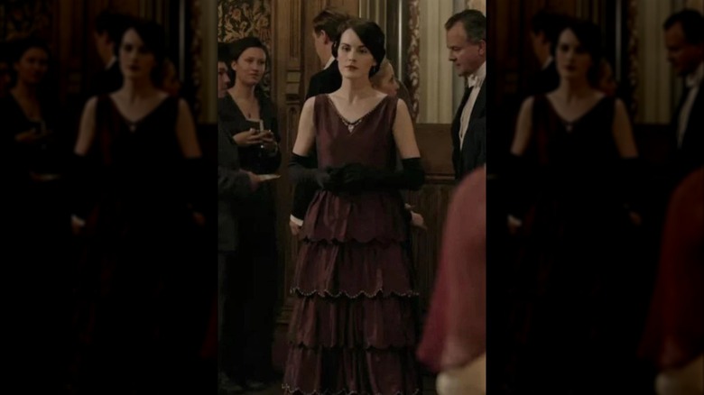 Michelle Dockery som Lady Mary iklädd en vinröd axelbandslös klänning och långa svarta handskar