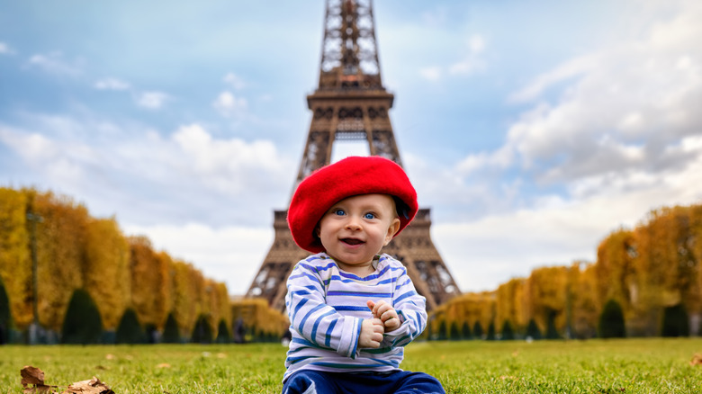 En bebis som bär en fransk hatt framför Eiffeltornet i Paris