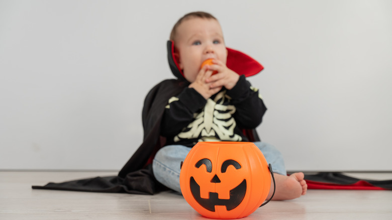 En baby i vampyrdräkt och pumpadekor.