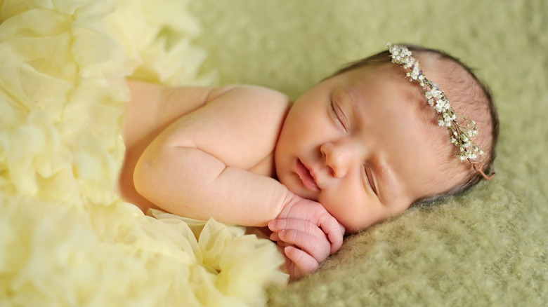 En baby som sover med ett blompannband