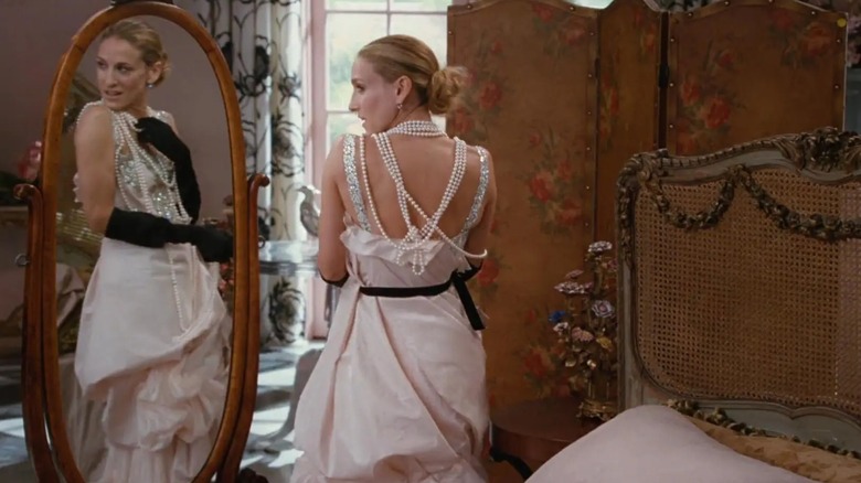 Sarah Jessica Parker som Carrie Bradshaw iklädd en draperad bröllopsklänning med svarta handskar och pärlhalsband.