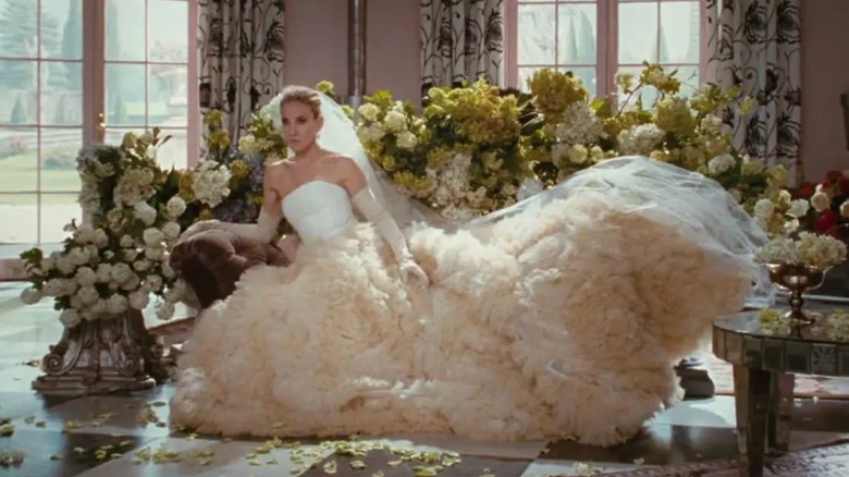 Sarah Jessica Parker som Carrie Bradshaw sitter ner klädd i en uttalande baldräkt bröllopsklänning och handskar.